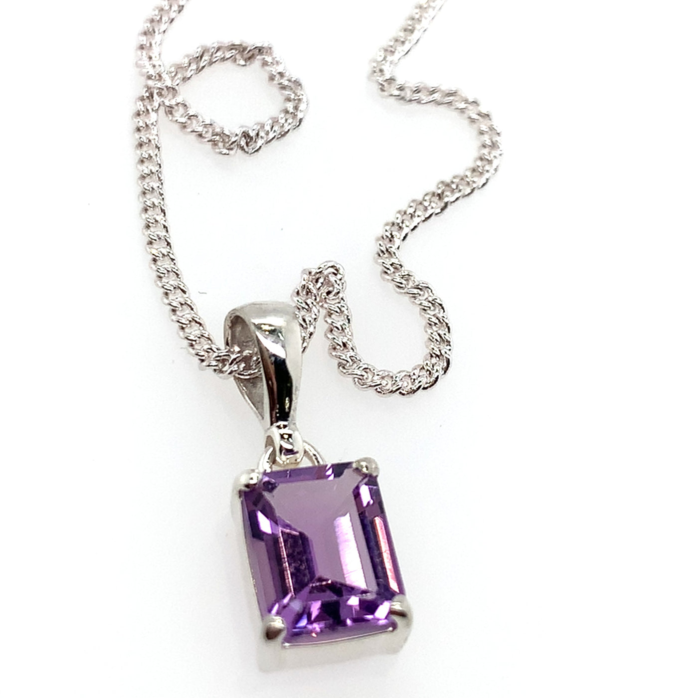 Purple gemstone pendant on a silver chain against a white background